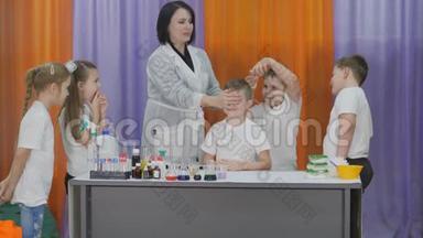儿童化学实验。 男孩把化学实验用的液体倒入带有粉末的塑料杯中。 儿童